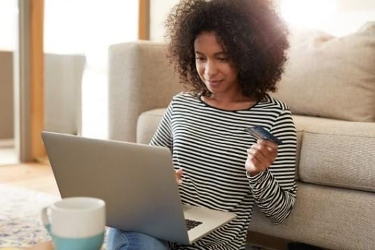 Frau mit Kreditkarte sitzt vor einem Laptop